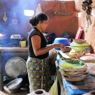 Woman cooking in traditional clay-pot jungle restaurant in Hiridunna VIllage